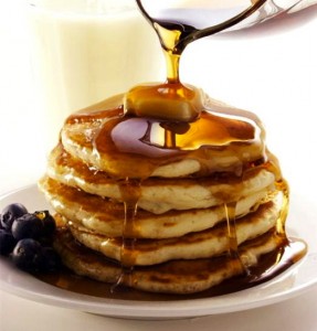 pouring_maple_syrup_over_a_stack_of_pancakes_9018652